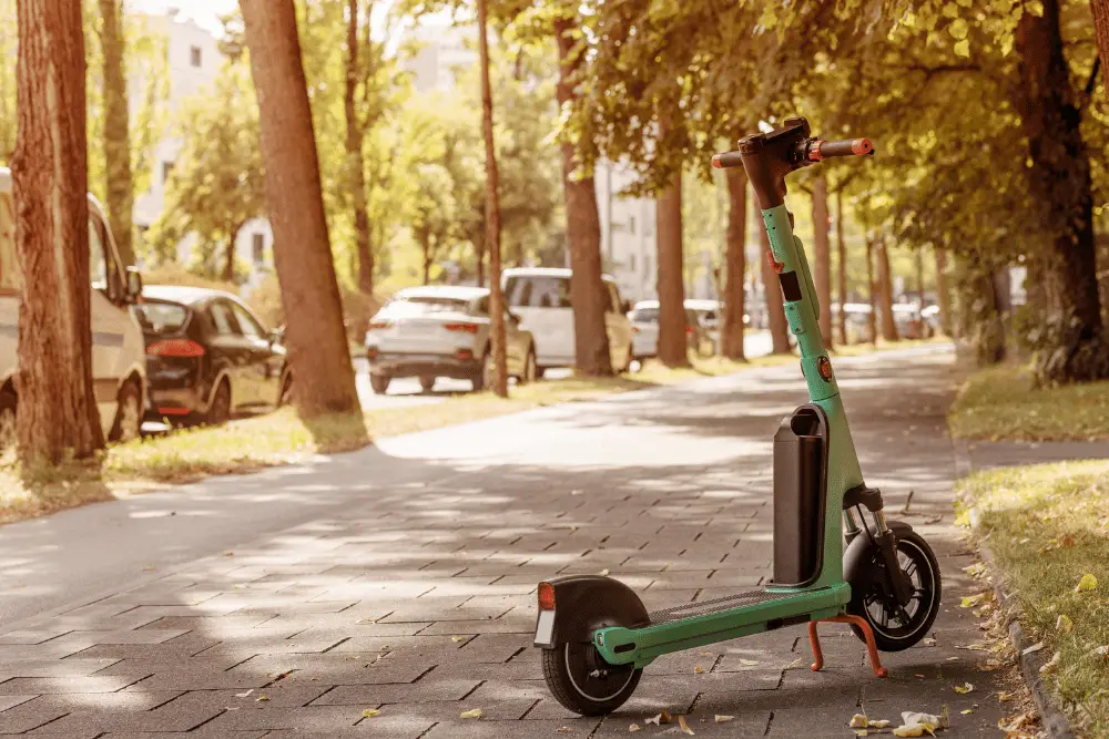 A light green and black electric scooter on a road side