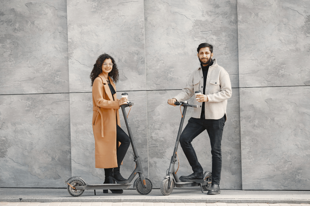 A couple with its electric scooter on a road side with cups of coffee