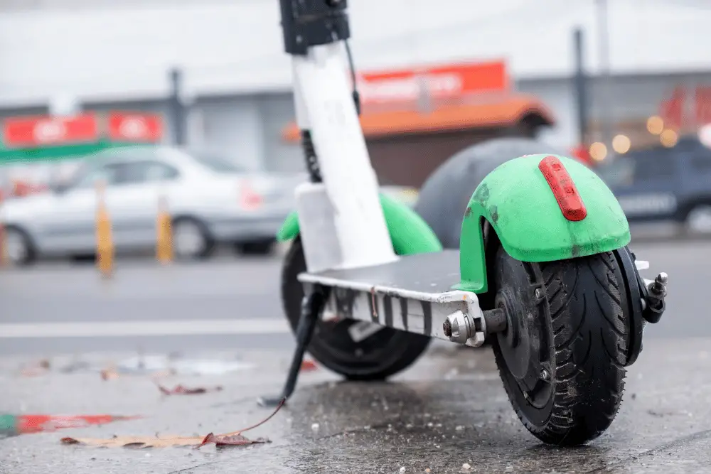A light green electric scooter with red tail light