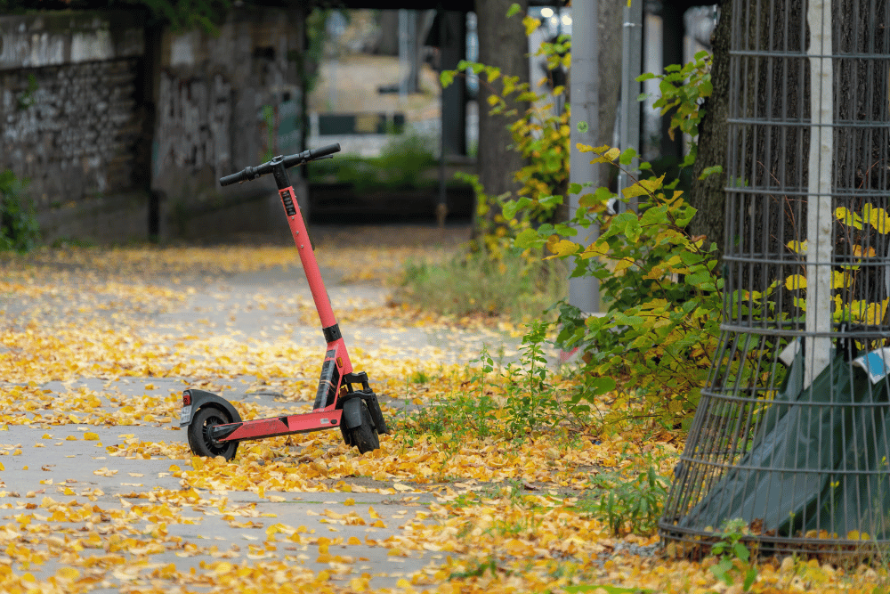 A reddish color electric scooter in summer days near dry plants
