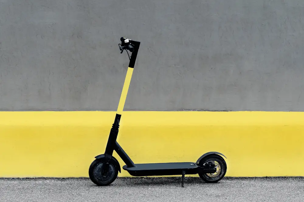 An electric scooter with a yellow sticker on handle