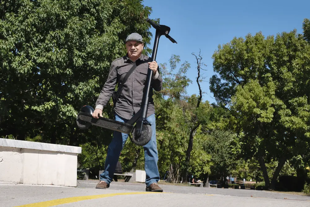 A man holding an electric scooter in one hand